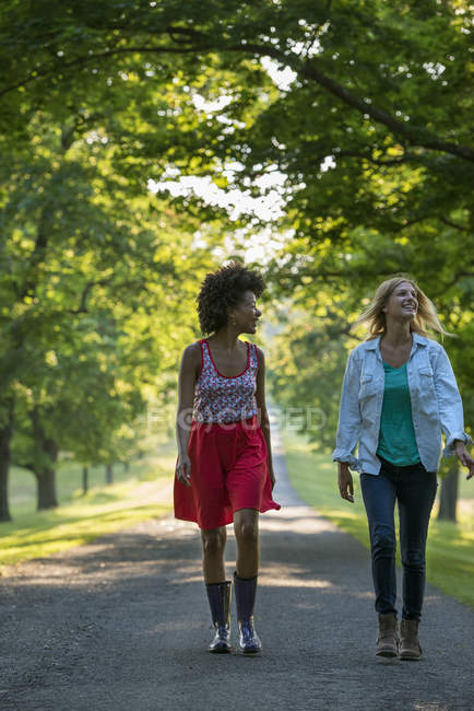 Two women walking down path in country park. — Stock Photo