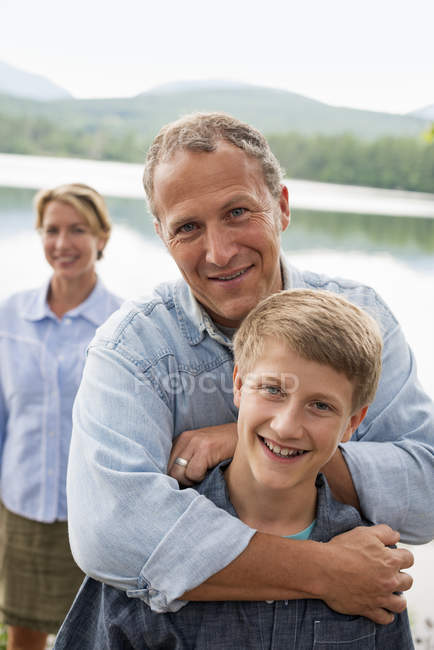 Family posing outdoors in woodland on lake shore. — Stock Photo