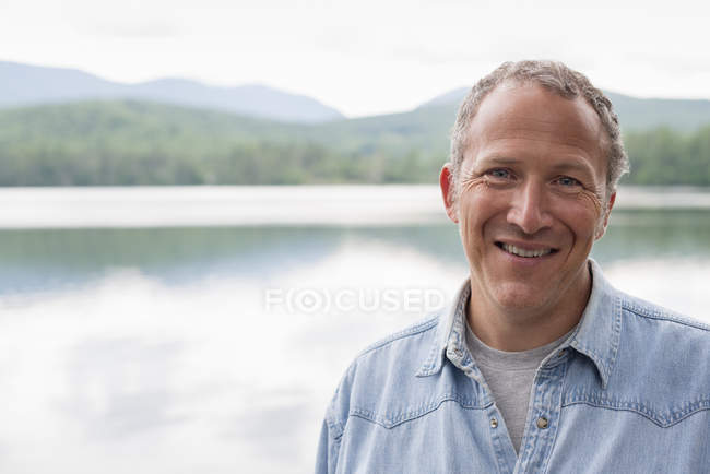 Portrait of man on shore of lake in countryside. — Stock Photo