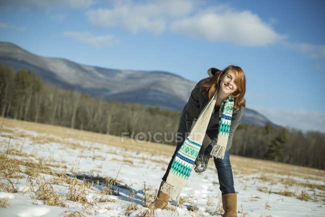 Junge Frau schaufelt Schneeball in verschneitem Feld in ländlicher Landschaft. — Stockfoto