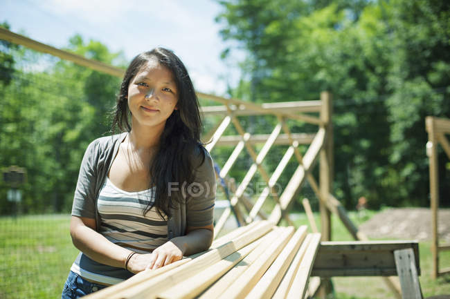 Mulher apoiada em troncos de madeira na fazenda tradicional no campo . — Fotografia de Stock