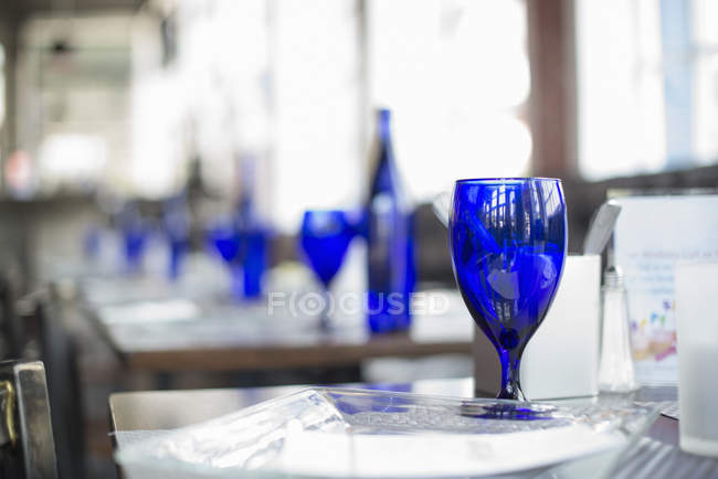 Bright blue glassware on empty tables of cafe. — Stock Photo