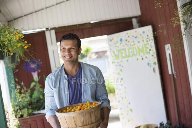 Mann hält Schale mit frisch gepflückten Tomaten in Bauernladen. — Stockfoto