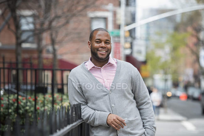 Hombre apoyado en la barandilla y sonriendo en la calle . - foto de stock