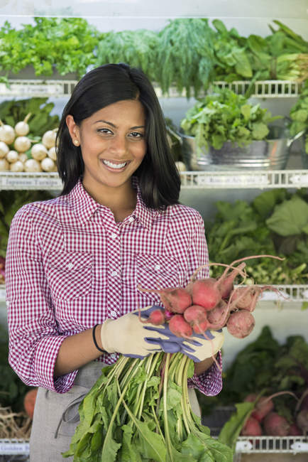 Young woman holding bunch of red beets at farmer store. — Stock Photo