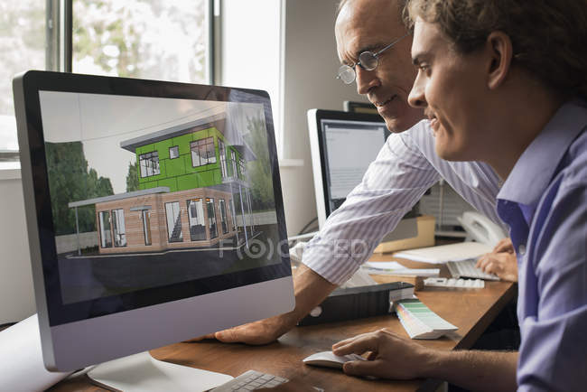 Архитекторы обсуждают проект зеленого строительства на компьютерном мониторе в офисе . — стоковое фото