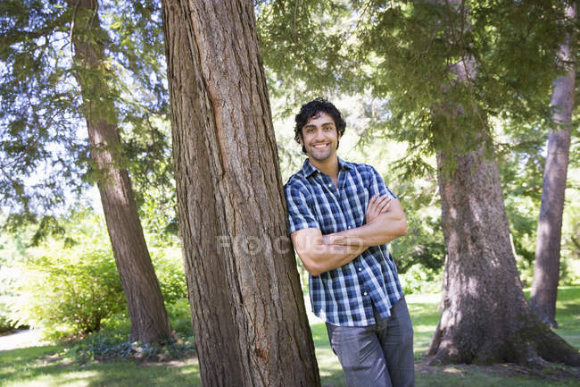 Молодий чоловік спирається на стовбур дерева в лісі . — стокове фото