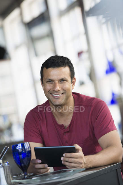 Mann sitzt am Cafétisch und nutzt digitales Tablet. — Stockfoto