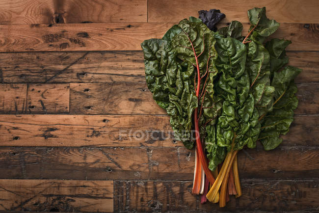 Chard leaves with bright colored stems on wooden board. — Stock Photo