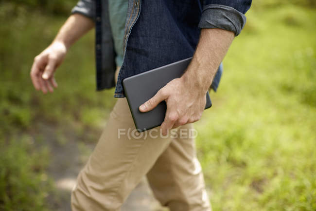 Vista ritagliata dell'uomo che trasporta tablet digitale all'aperto . — Foto stock