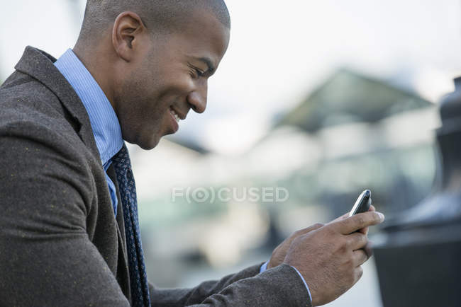 Hombre adulto en traje comprobando teléfono inteligente, vista lateral . - foto de stock