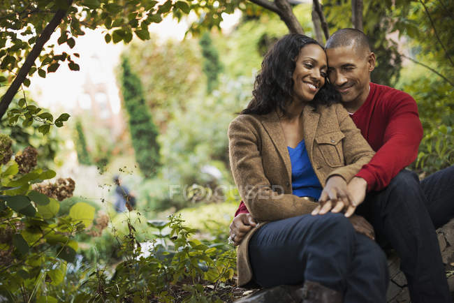 Casal adulto médio sentado junto sob árvores no parque da cidade . — Fotografia de Stock