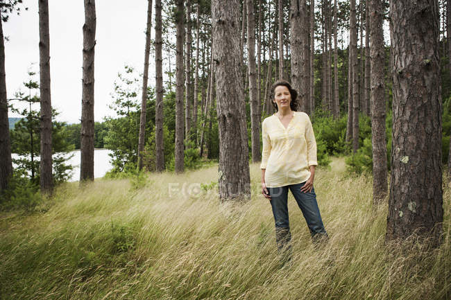 Woman standing in tall grass on country lake shore — Stock Photo