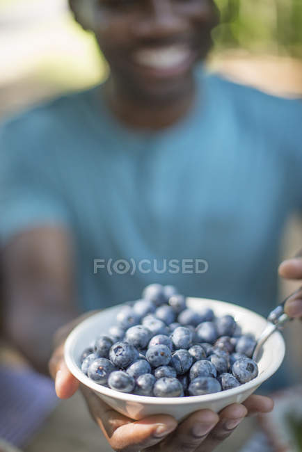 Man holding bowl of fresh blueberries outdoors. — Stock Photo