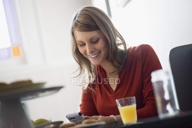 Junge Frau benutzt Smartphone, während sie am Tisch im Café sitzt. — Stockfoto