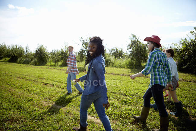 Groupe de jeunes hommes et femmes marchant dans le champ agricole de la campagne . — Photo de stock
