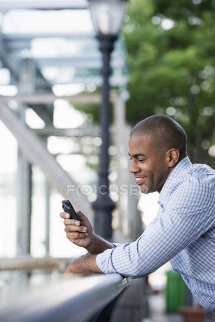 Hombre adulto en camisa revisando smartphone, vista lateral
. - foto de stock