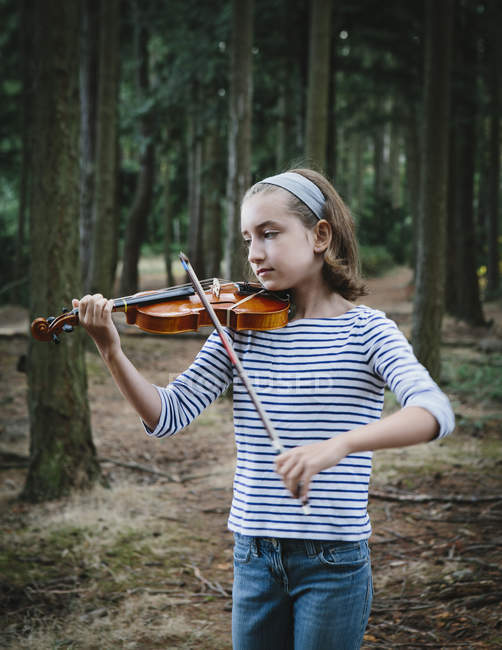 Pre-adolescent female violinist playing violin in forest. — Stock Photo