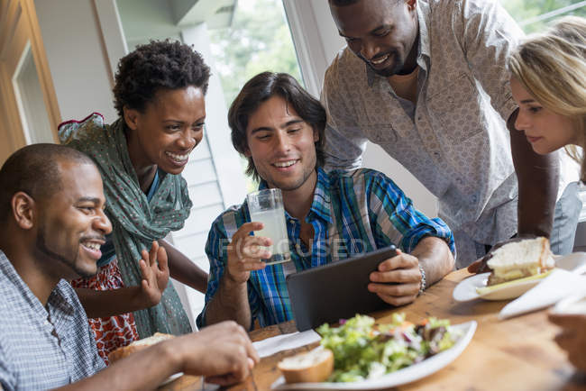 Група людей, які обідали і використовували цифровий планшет на зустрічі в кафе . — стокове фото