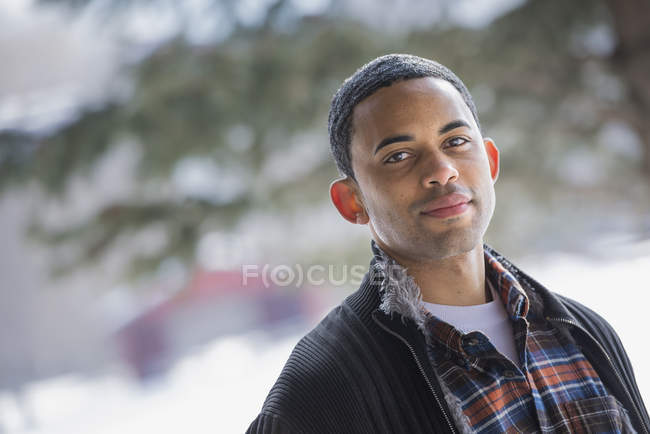 Man wearing plaid shirt and open jacket standing outdoors. — Stock Photo