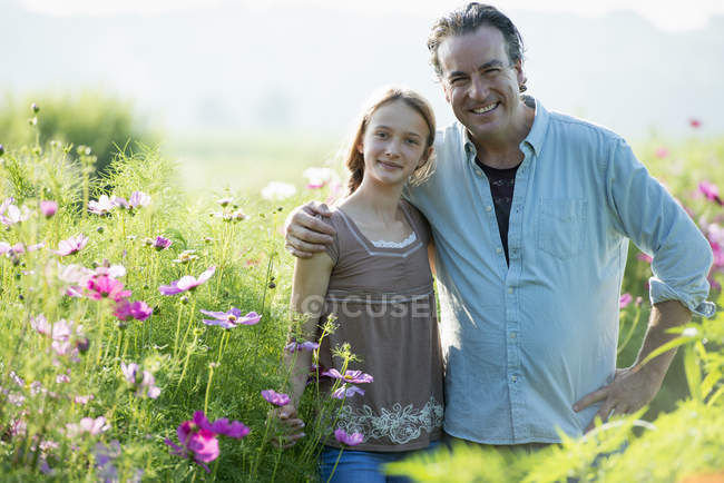 Зрелый мужчина с дочерью позируют в зеленом поле цветов . — стоковое фото