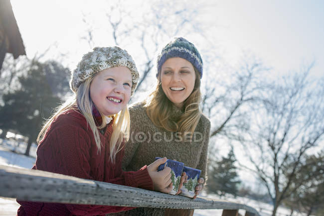 Menina e mulher adulta tendo bebidas quentes na paisagem de inverno . — Fotografia de Stock