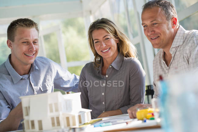 Female and male designers working on model of farmhouse at table in countryside. — Stock Photo