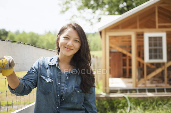 Junge Frau lehnt an Zaun auf traditionellem Bauernhof im Grünen. — Stockfoto