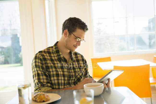 Jeune homme utilisant une tablette numérique dans un café . — Photo de stock