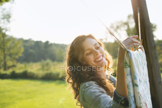 Молодая женщина висит прачечная на стиральной линии в сельской местности . — стоковое фото