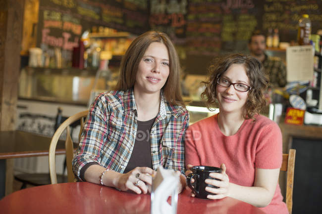 Femmes assises à table dans un café avec un homme en arrière-plan
. — Photo de stock