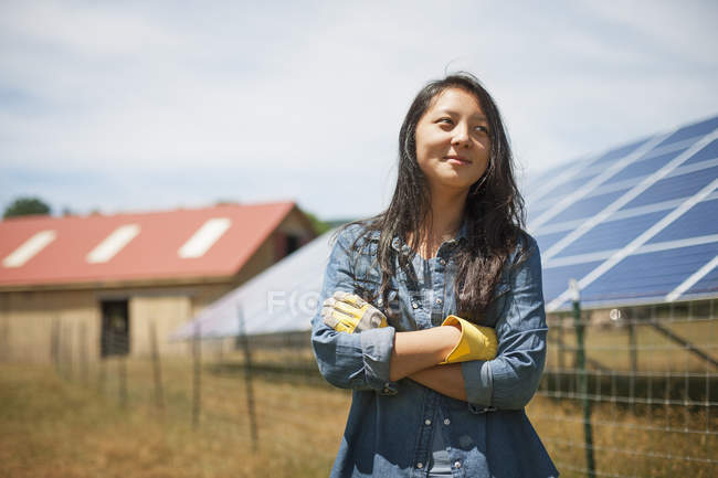 Jovem mulher em pé na frente do painel solar na fazenda no campo . — Fotografia de Stock