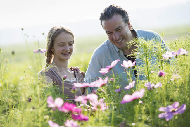Mature man and girl looking at flowers in farm field. — Stock Photo