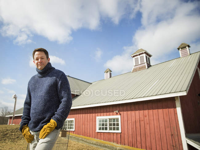 Hombre posando frente al edificio del granero en la granja . - foto de stock