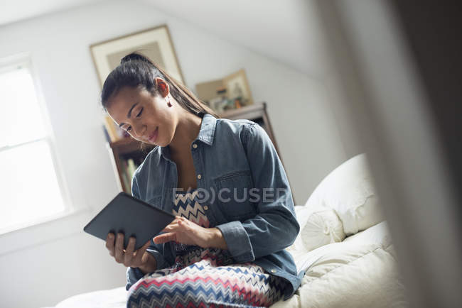 Молодая женщина с помощью цифрового планшета на кровати в помещении . — стоковое фото