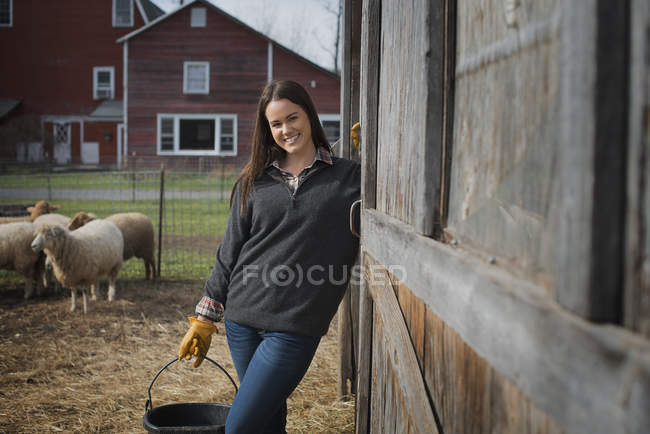 Joven agricultora sosteniendo cubo de agua en la granja . - foto de stock