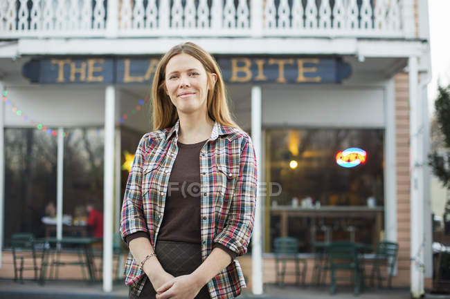 Молодая женщина стоит перед вывеской уличного кафе
. — стоковое фото