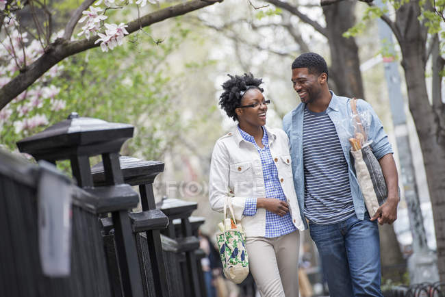 Paar läuft Seite an Seite im Park und trägt Einkaufstüten. — Stockfoto