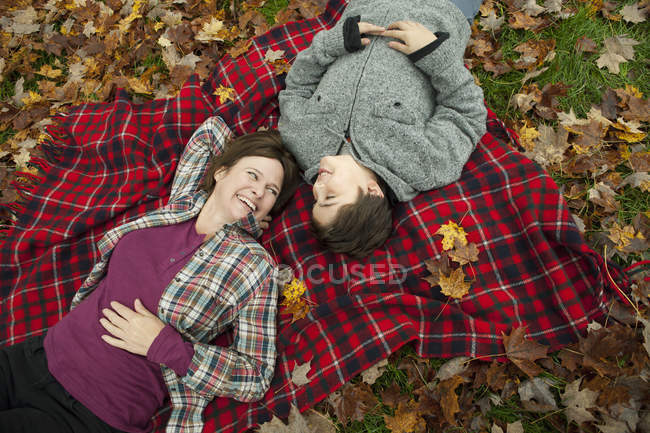 Vue aérienne de la femme et de l'enfant couchés sur une couverture de pique-nique en tartan . — Photo de stock