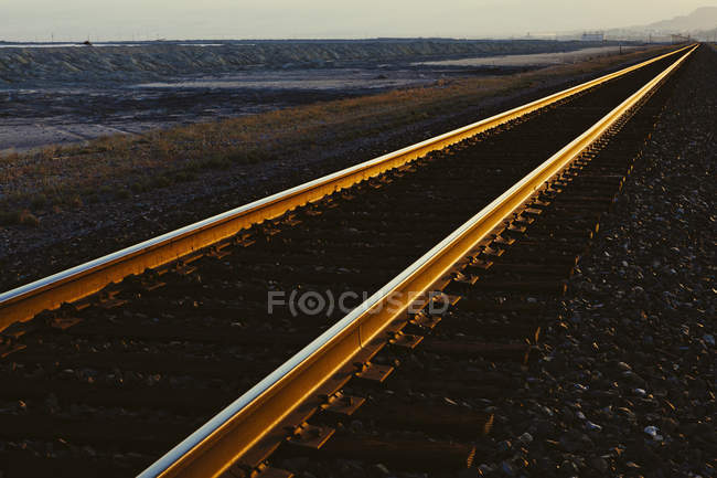 Caminhos de ferro que se estendem através da paisagem plana do deserto de Utah ao entardecer, EUA . — Fotografia de Stock