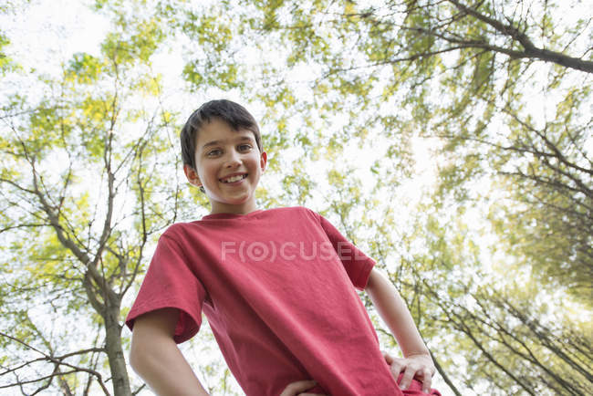 Visão de baixo ângulo do menino pré-adolescente posando na floresta . — Fotografia de Stock