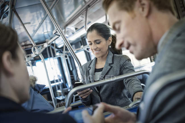 Men talking on bus with woman using smartphone in background. — Stock Photo