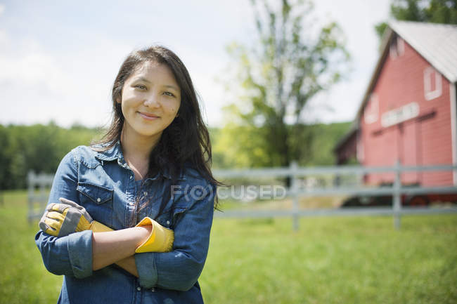 Junge Frau steht vor traditionellem Bauernhaus auf dem Land. — Stockfoto