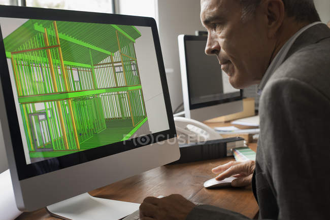 Архитектор, работающий над проектом зеленого строительства на компьютерном мониторе в офисе . — стоковое фото