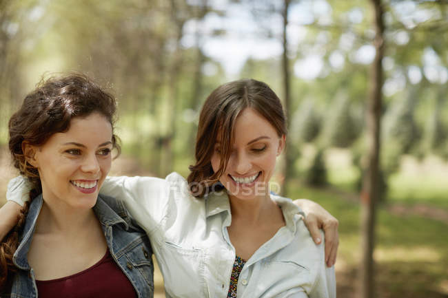 Two female friends smiling and embracing in woodland. — Stock Photo