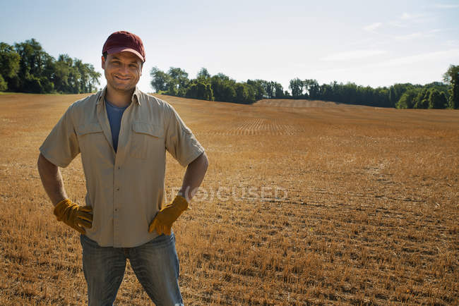 Человек с руками на бедрах стоит у свежевспаханного поля
. — стоковое фото