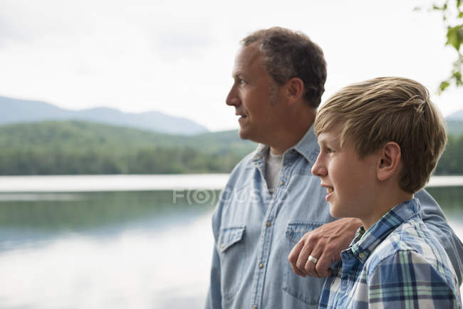 Padre e figlio in piedi all'aperto sulla riva del lago e guardando la vista . — Foto stock