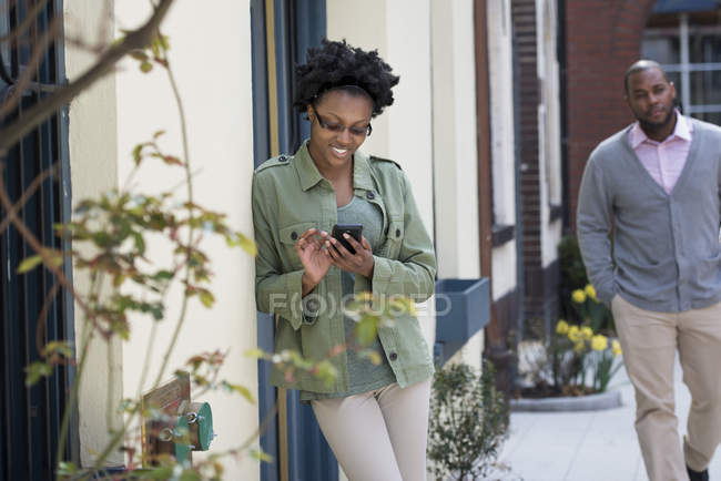 Homem se aproximando mulher inclinada na parede e verificando smartphone . — Fotografia de Stock