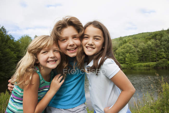 Три девушки позируют бок о бок перед лесным озером . — стоковое фото