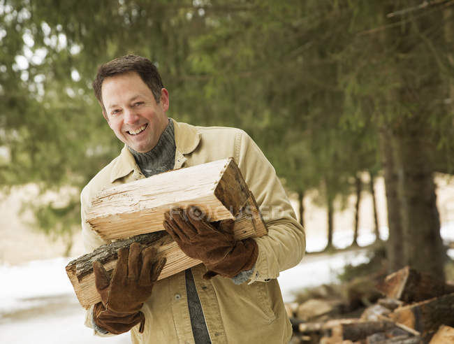Uomo maturo posa con tronchi di legno in campagna
. — Foto stock